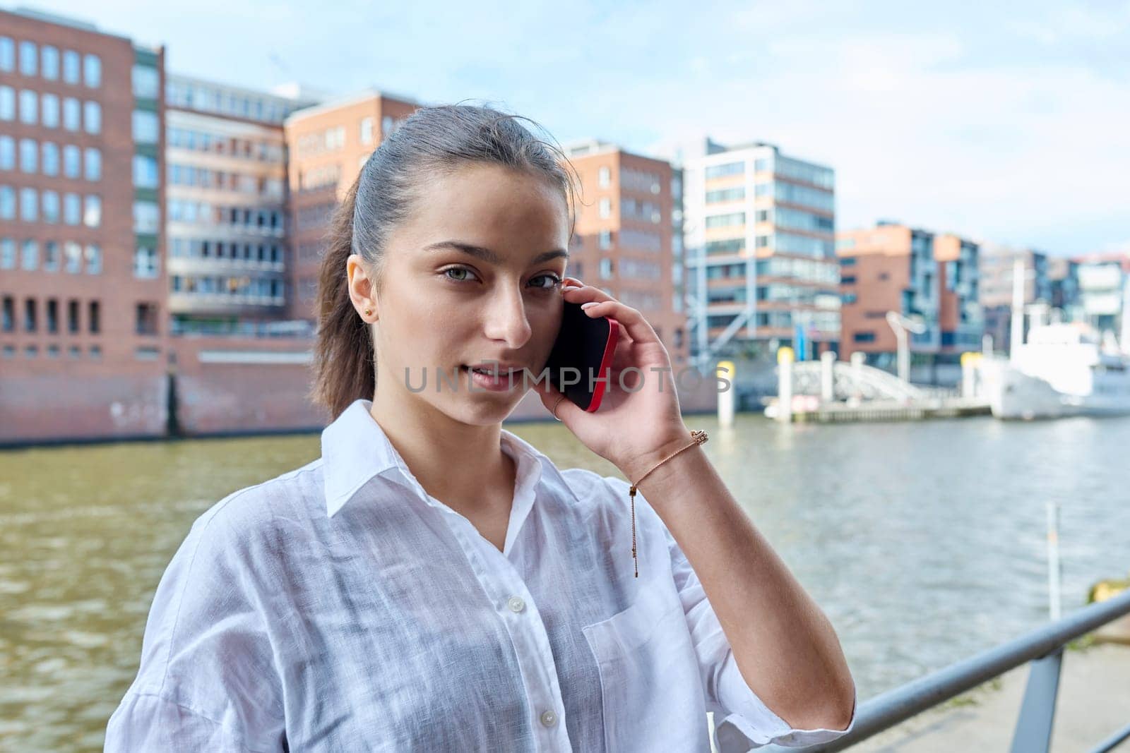 Young attractive teenage girl talking on mobile phone, outdoor on modern city. Teenager, college student communicating on smartphone. Urban style, communication, lifestyle, youth
