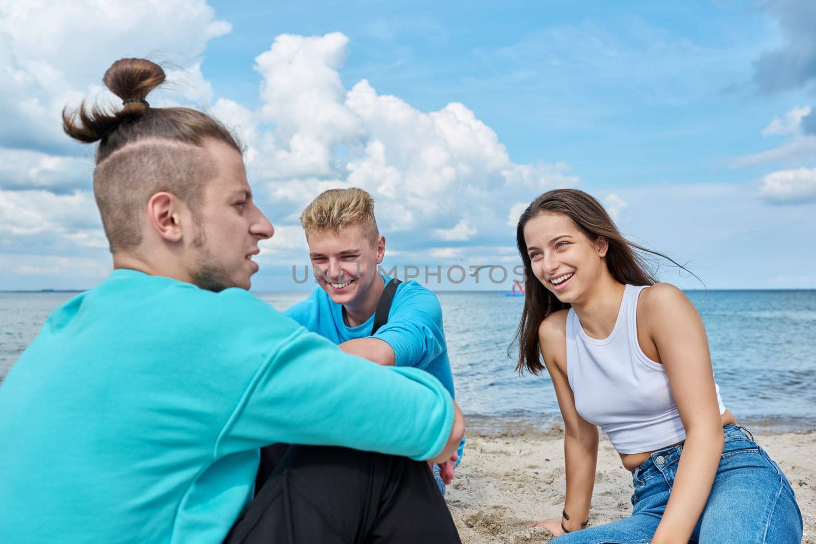 Friends teenagers talking sitting on sand on beach by VH-studio