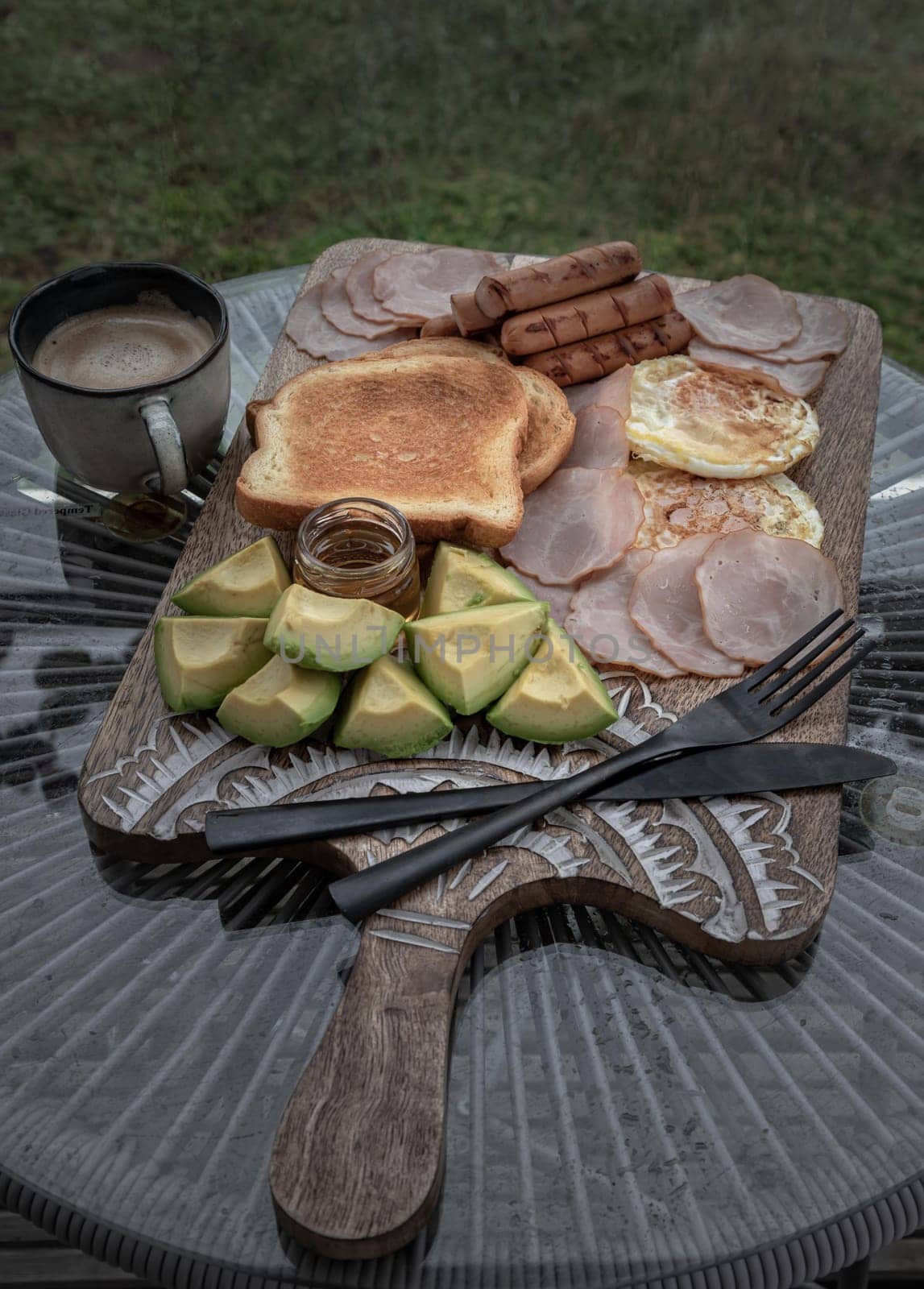 breakfast is including Fried sausages, Fried eggs, Toast breads and cut avocados served with Honey and Cup of coffee. by tosirikul