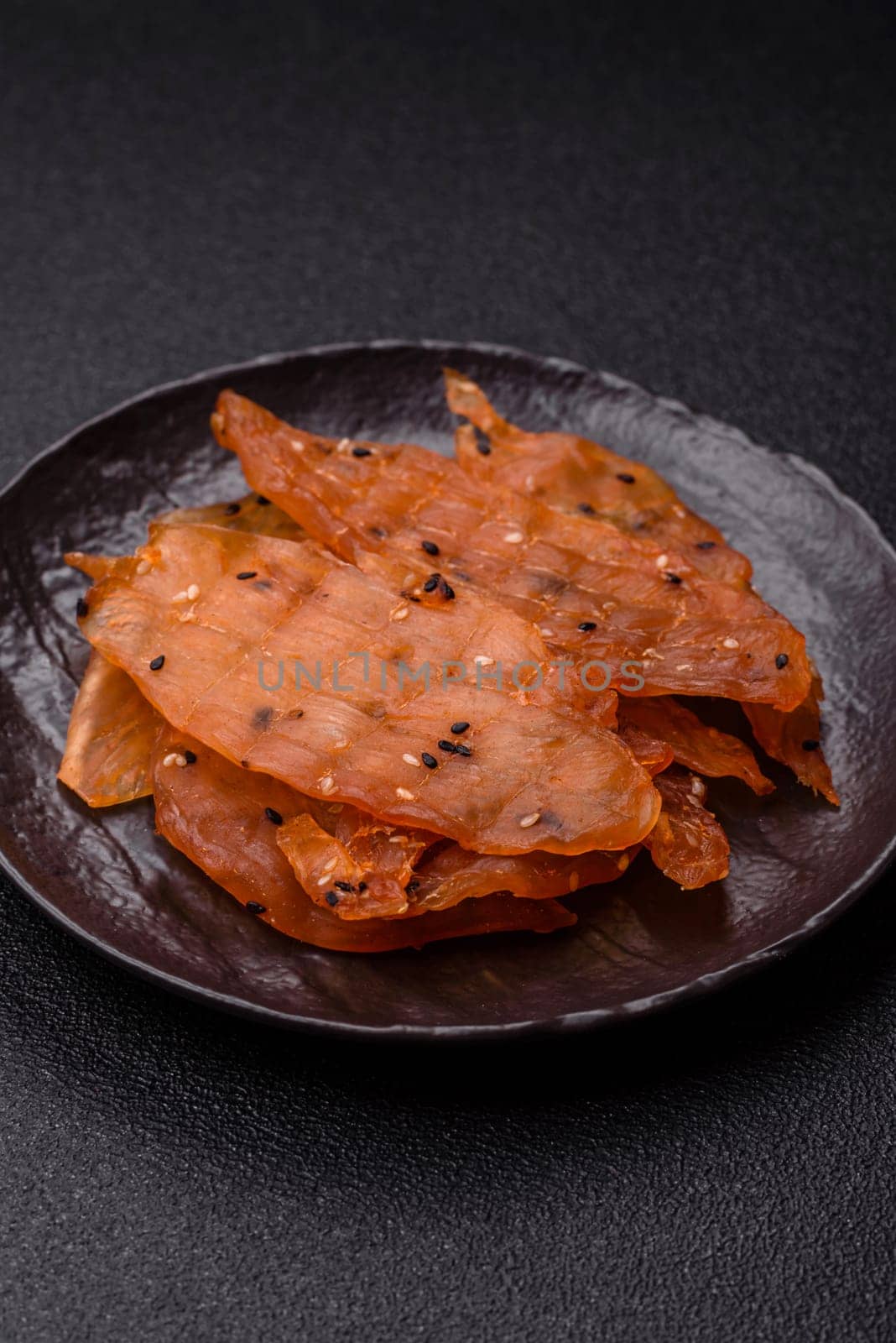 Jerky, dried chicken meat with salt and spices on a dark concrete background