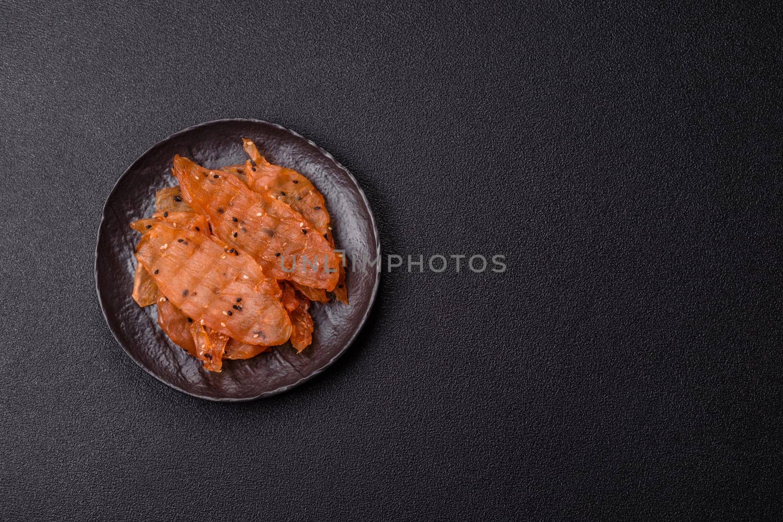 Jerky, dried chicken meat with salt and spices on a dark concrete background
