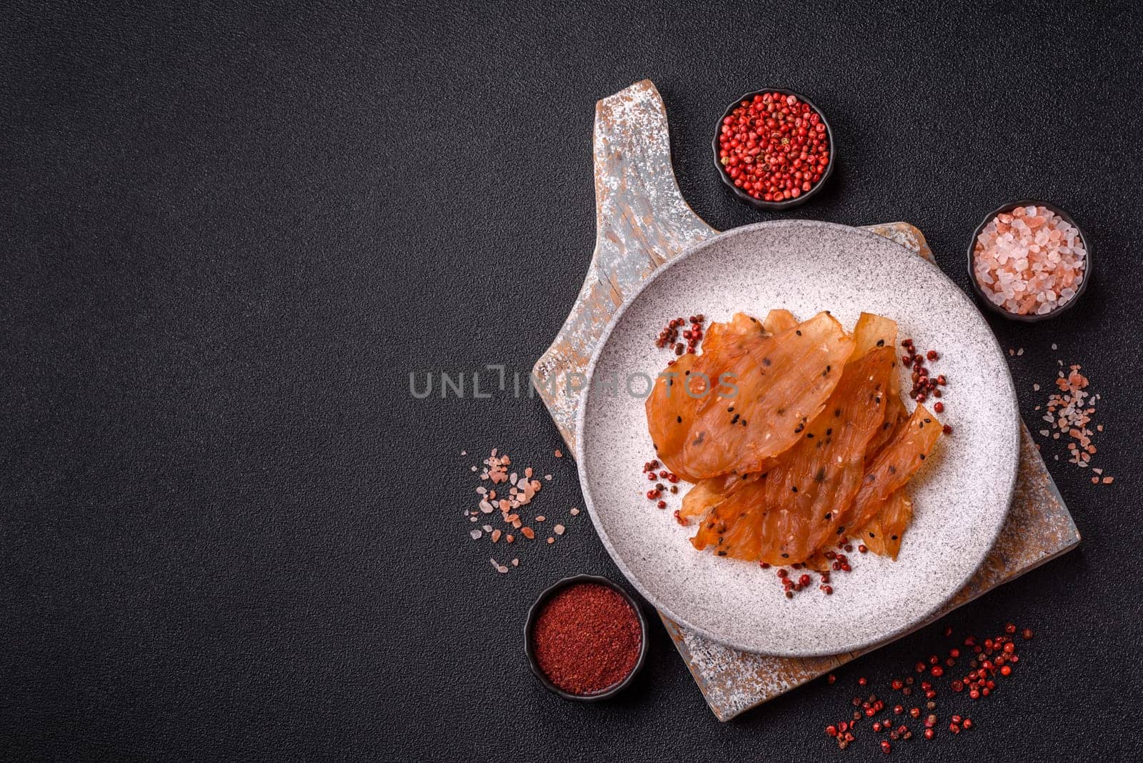 Jerky, dried chicken meat with salt and spices on a dark concrete background