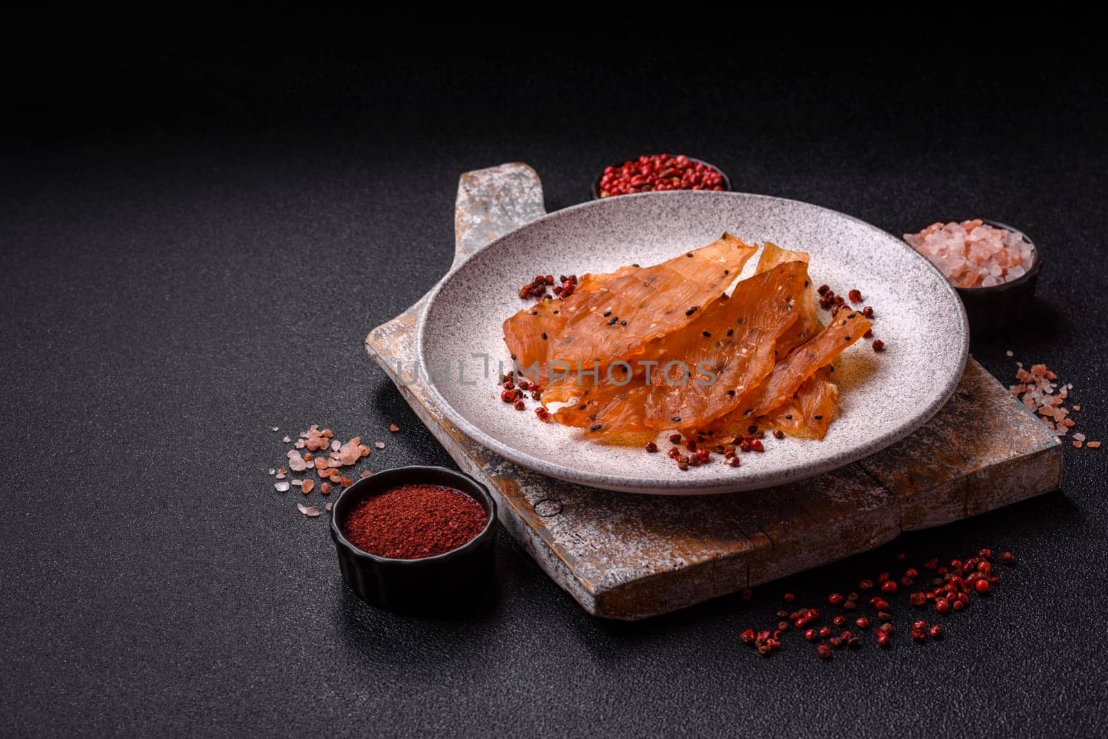 Jerky, dried chicken meat with salt and spices on a dark concrete background