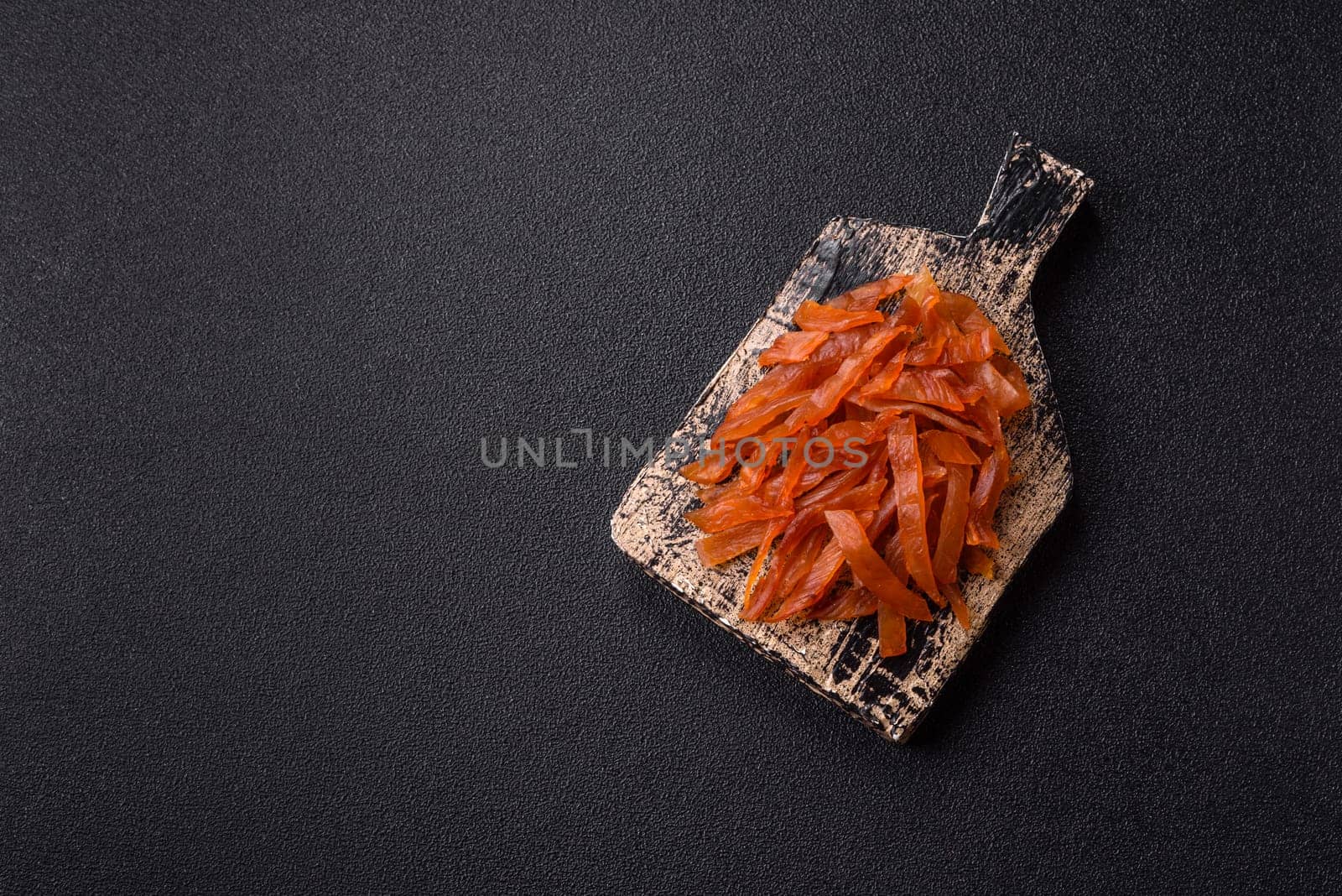 Jerky, dried turkey meat with salt and spices on a dark concrete background