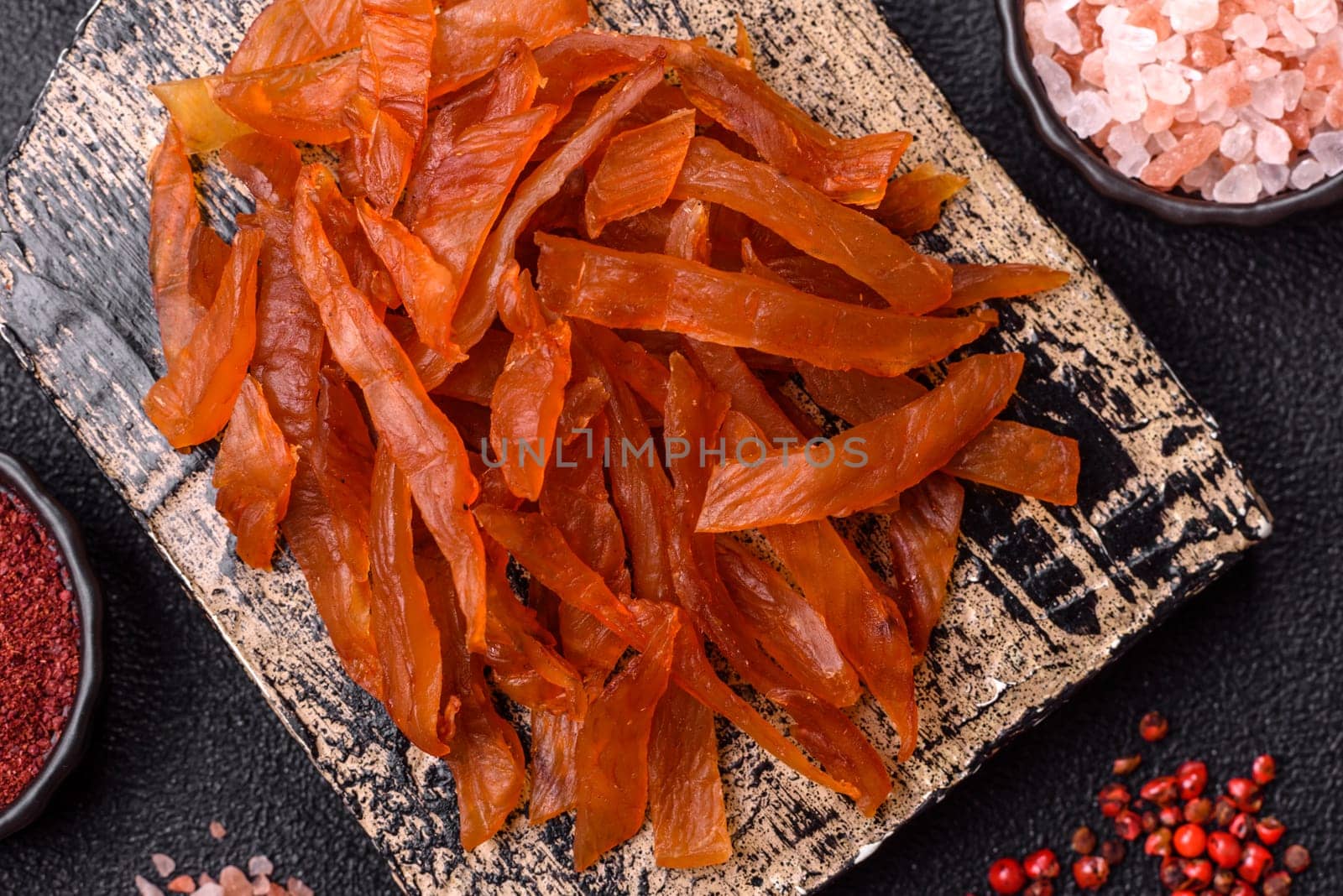 Jerky, dried turkey meat with salt and spices on a dark concrete background
