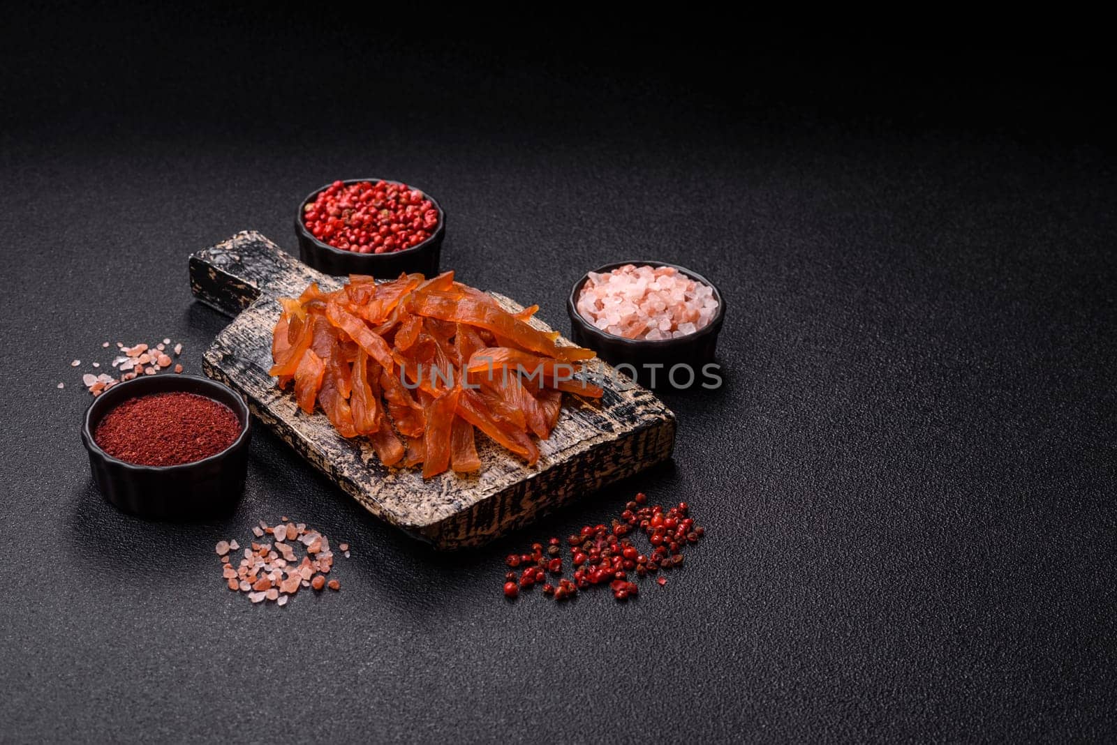 Jerky, dried turkey meat with salt and spices on a dark concrete background