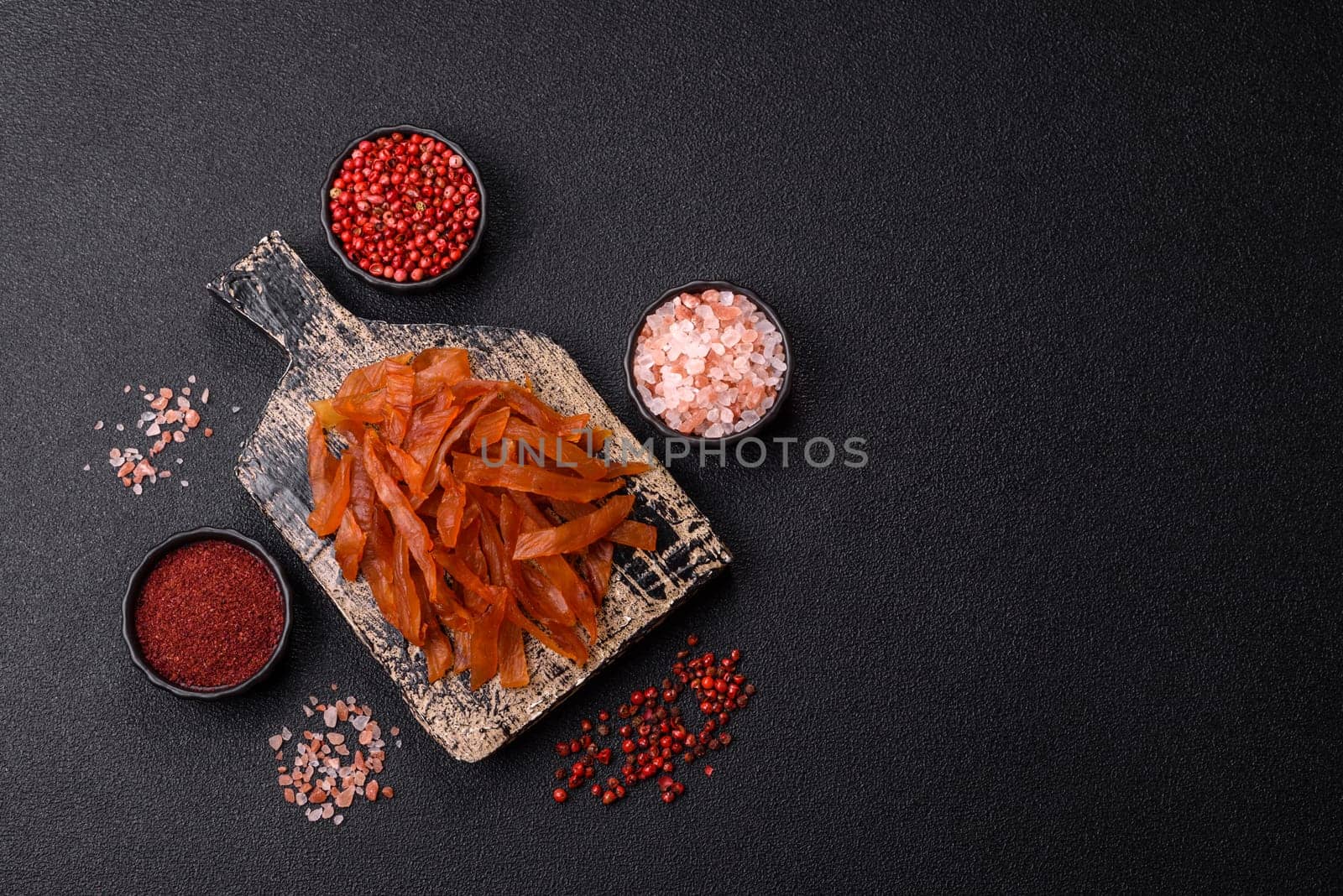 Jerky, dried turkey meat with salt and spices on a dark concrete background
