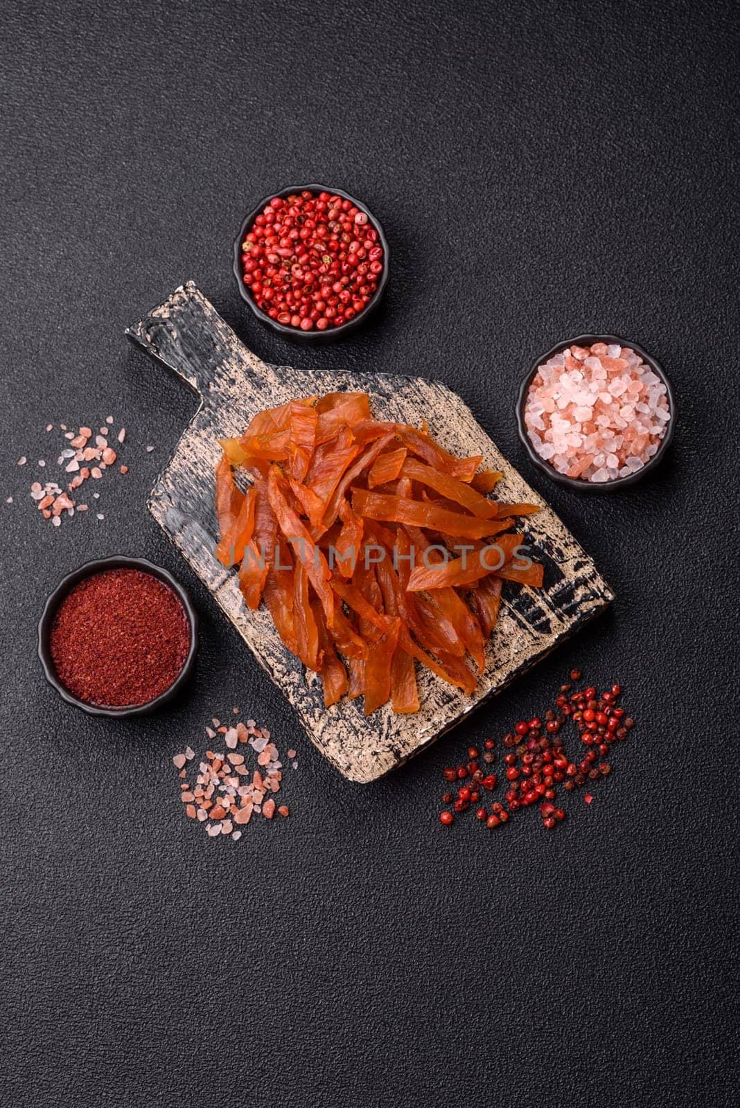 Jerky, dried turkey meat with salt and spices on a dark concrete background