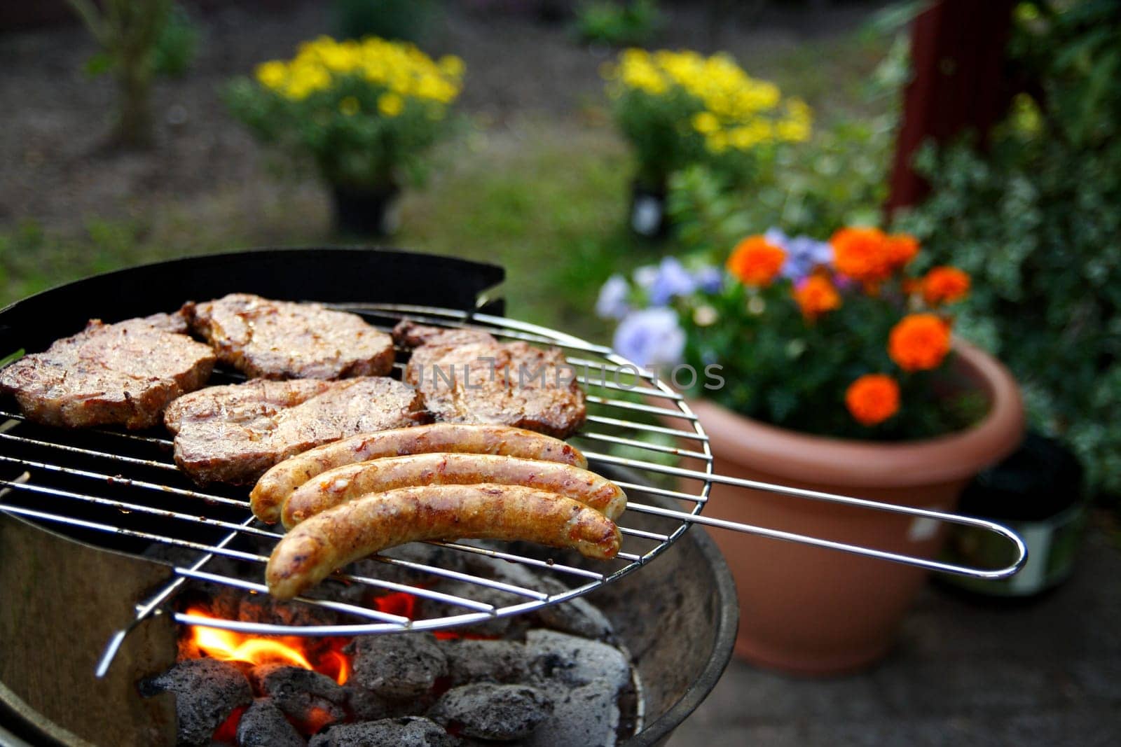 Grill with grilled meat and bratwurst in the garden