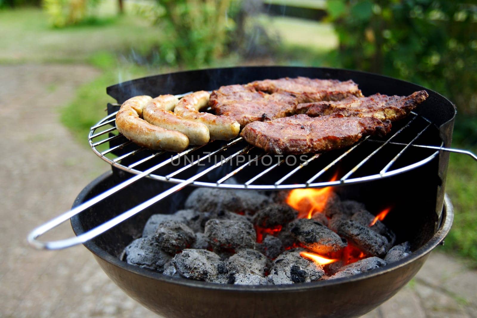 Grill with grilled meat and bratwurst in the garden