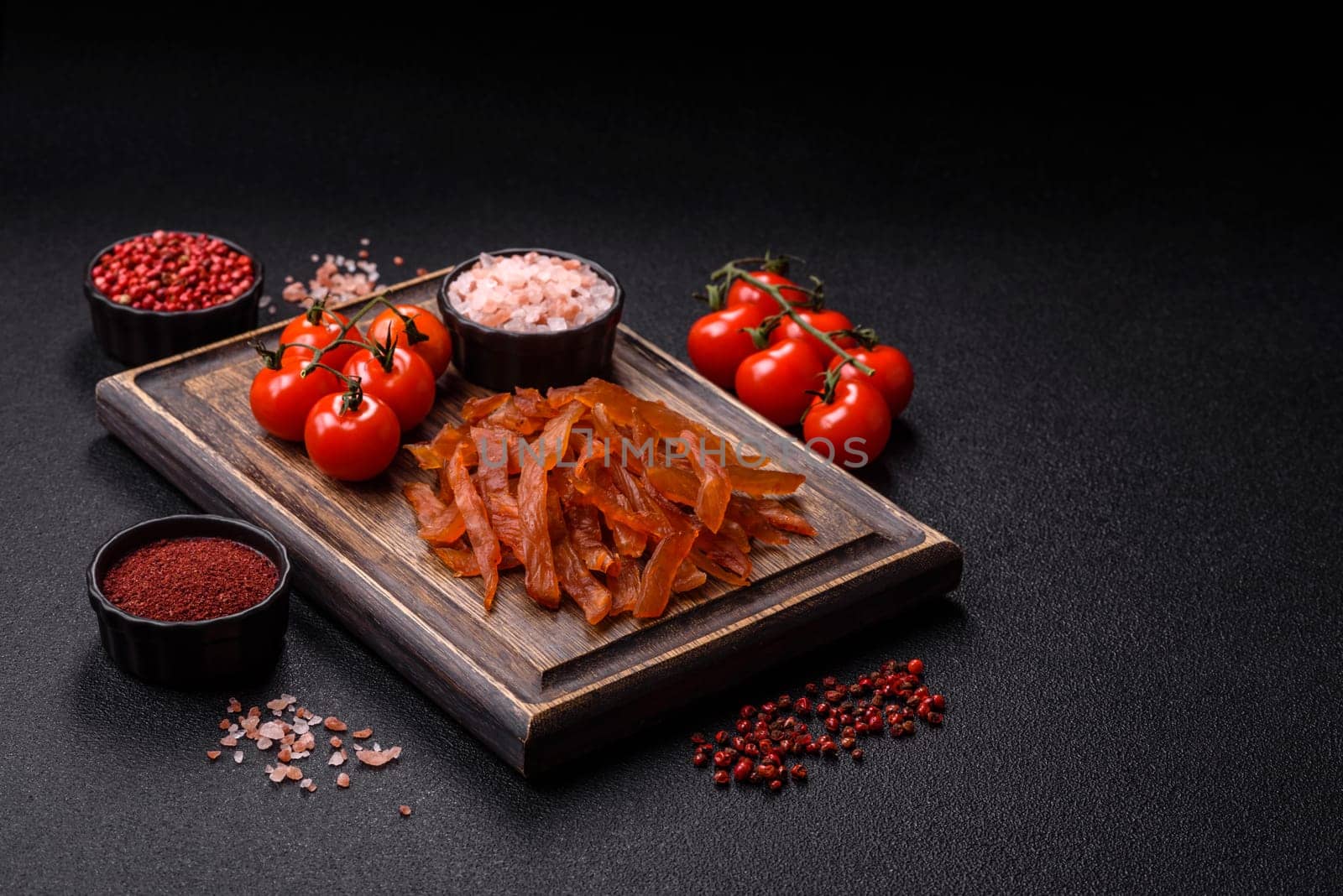 Jerky, dried turkey meat with salt and spices on a dark concrete background