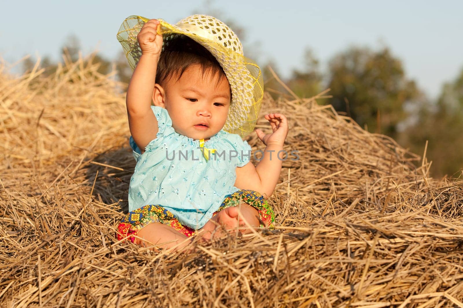 Baby girl from Asia sits on straw