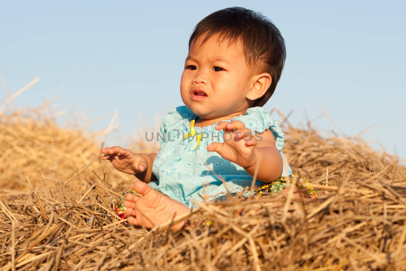 Baby girl from Asia sits on straw