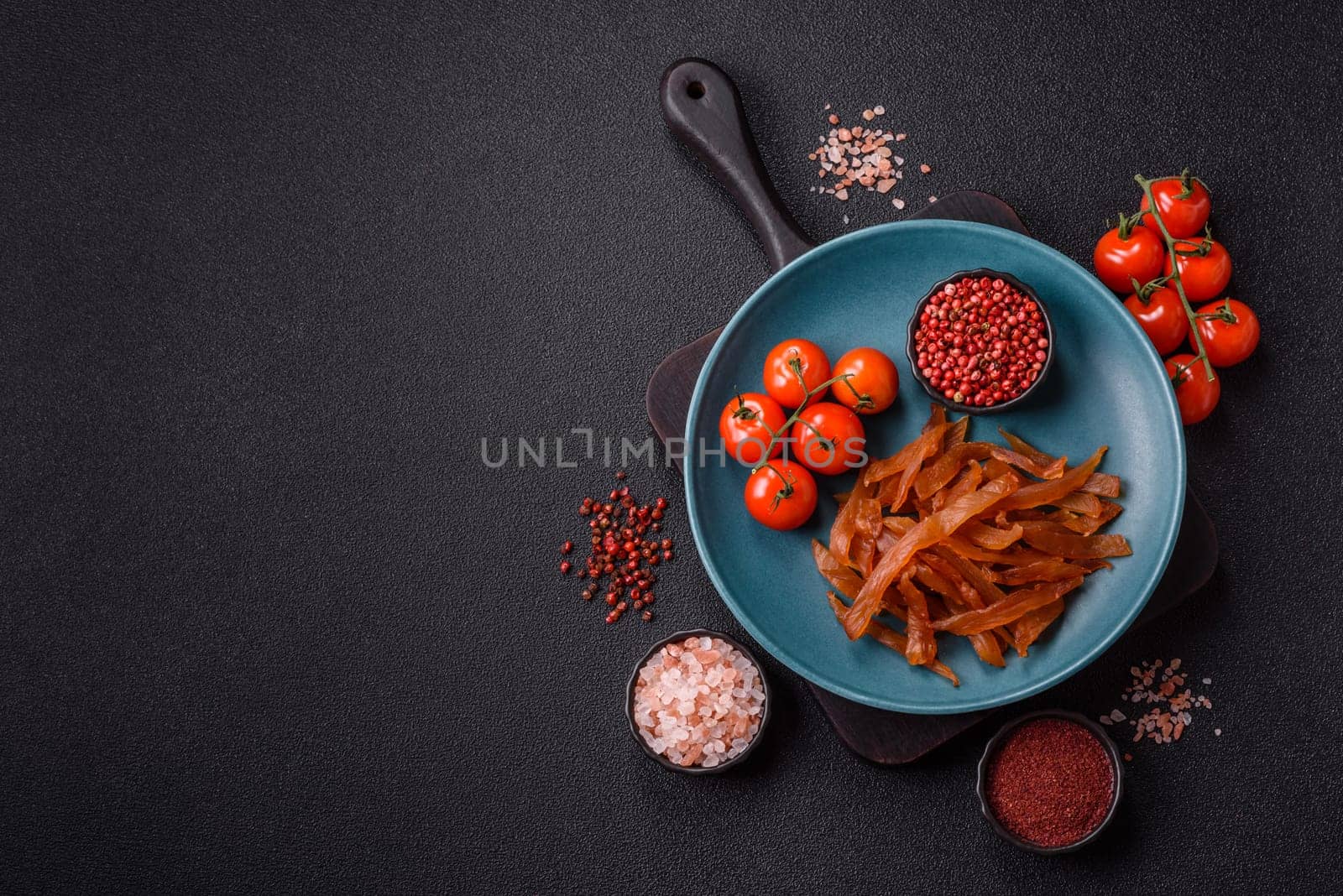 Jerky, dried turkey meat with salt and spices on a dark concrete background