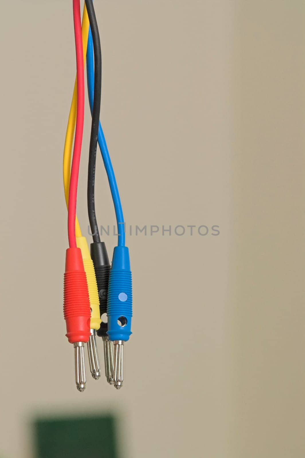 A tangle of interwoven male connectors against a wall and a circuit in the backg