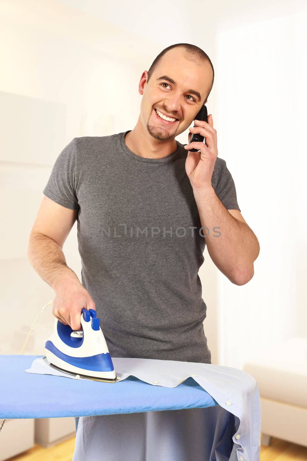 young man ironing his clothes and speat at mobile