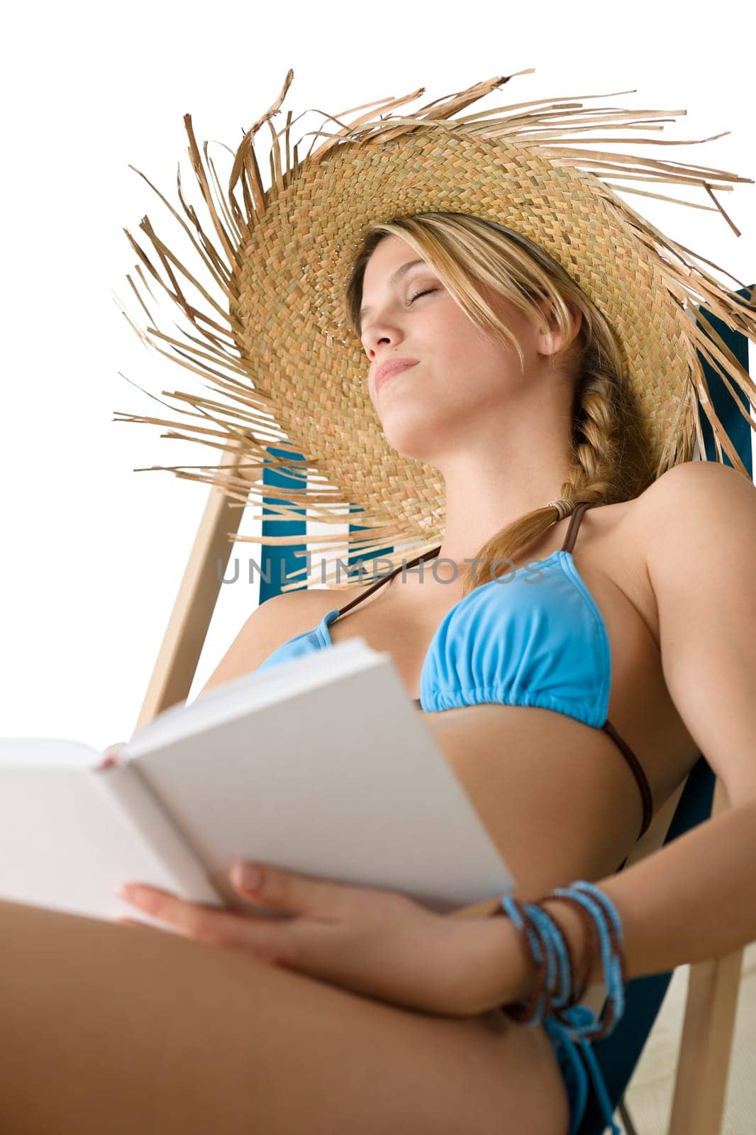 Beach - Young woman in bikini sitting on deck chair