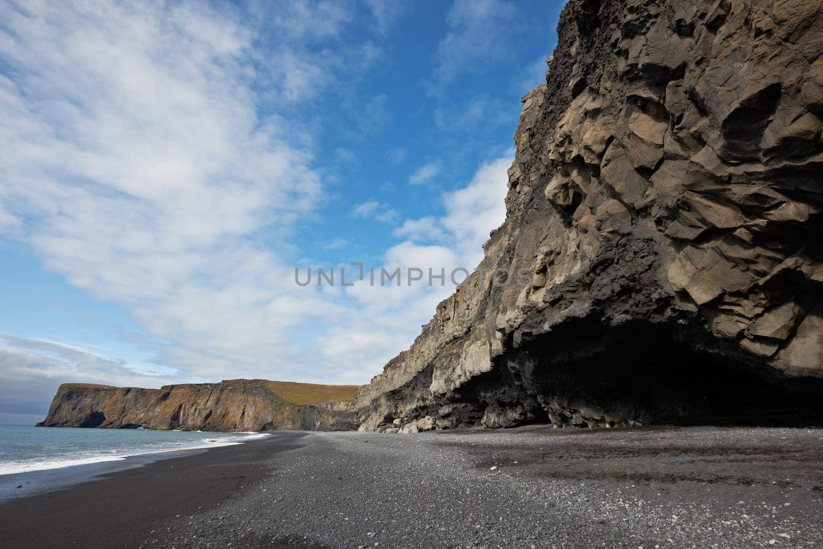 Black sand beach with Lundadrangur Rock Arch in Dyrholaey, South