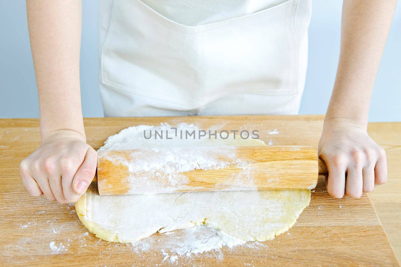 Hands with rolling pin and cookie dough
