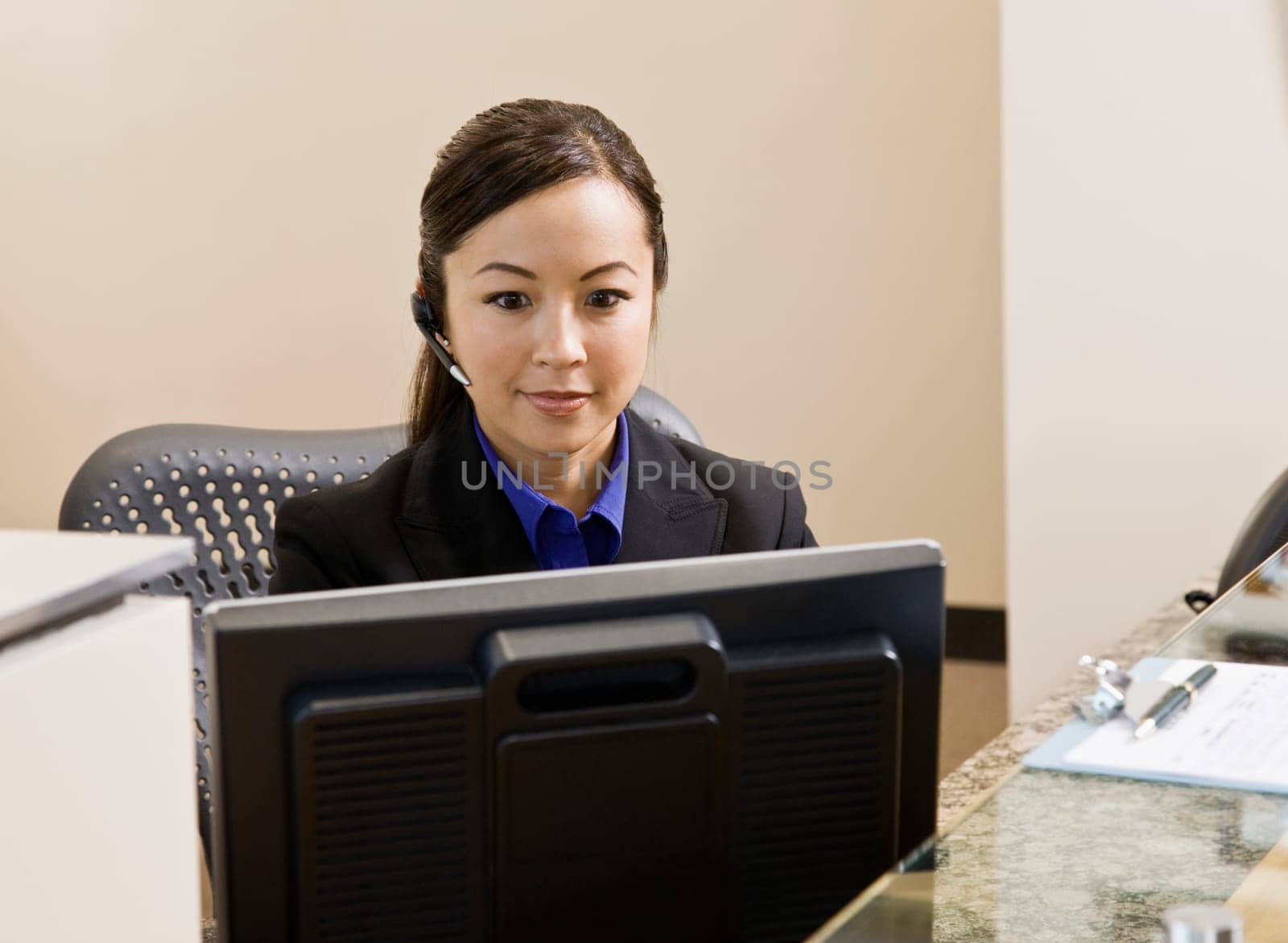 Young woman sitting at desk in front of computer. Horizontally framed shot.