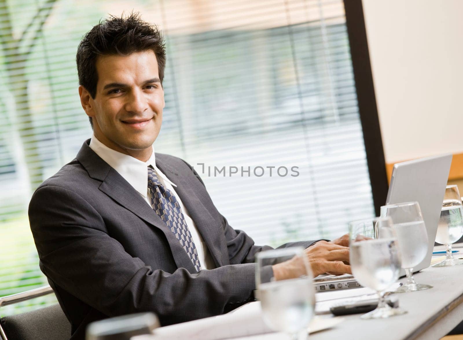 Man in business suit smiling working on laptop. Horizontally framed shot.