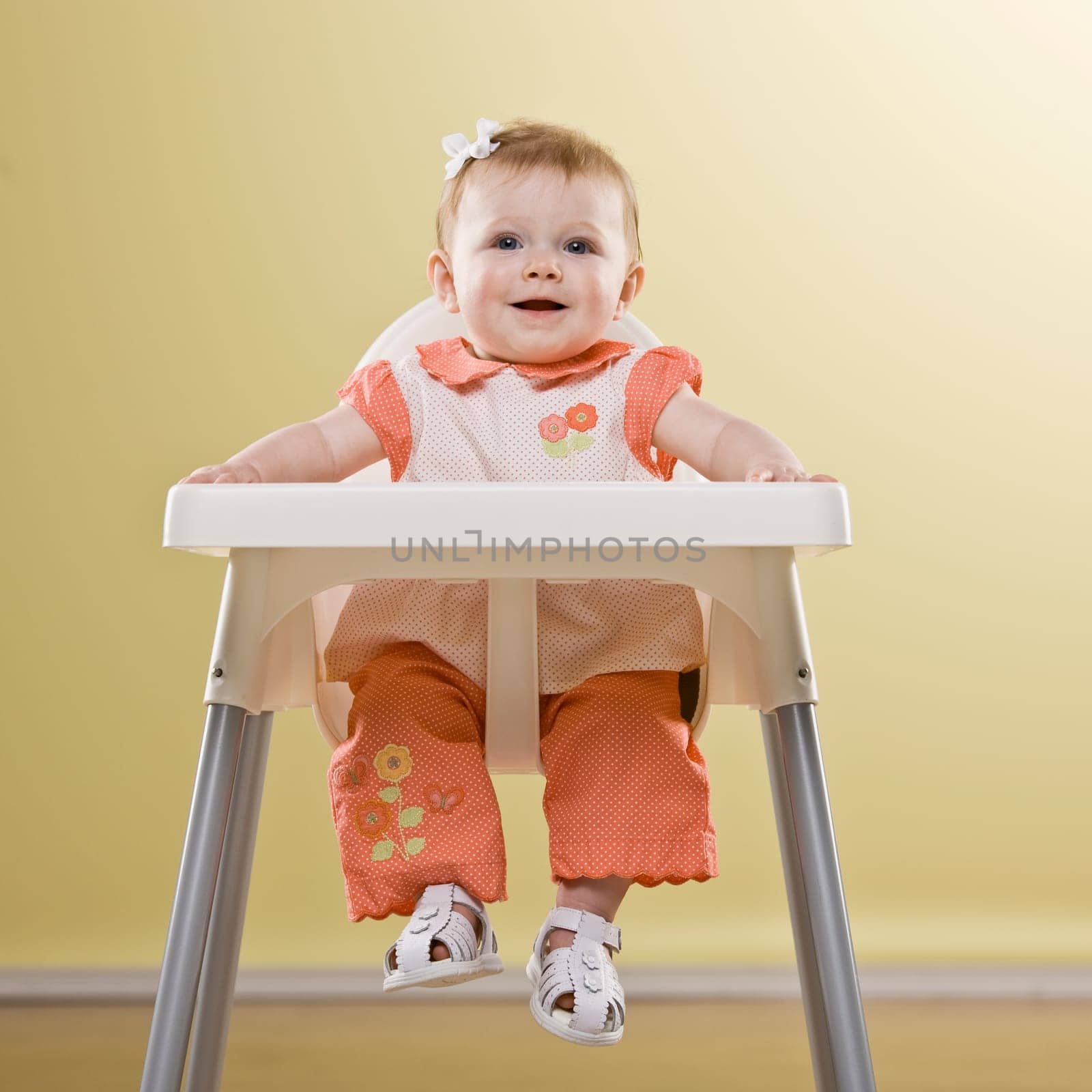 Baby girl in high chair smiling. Square framed shot.