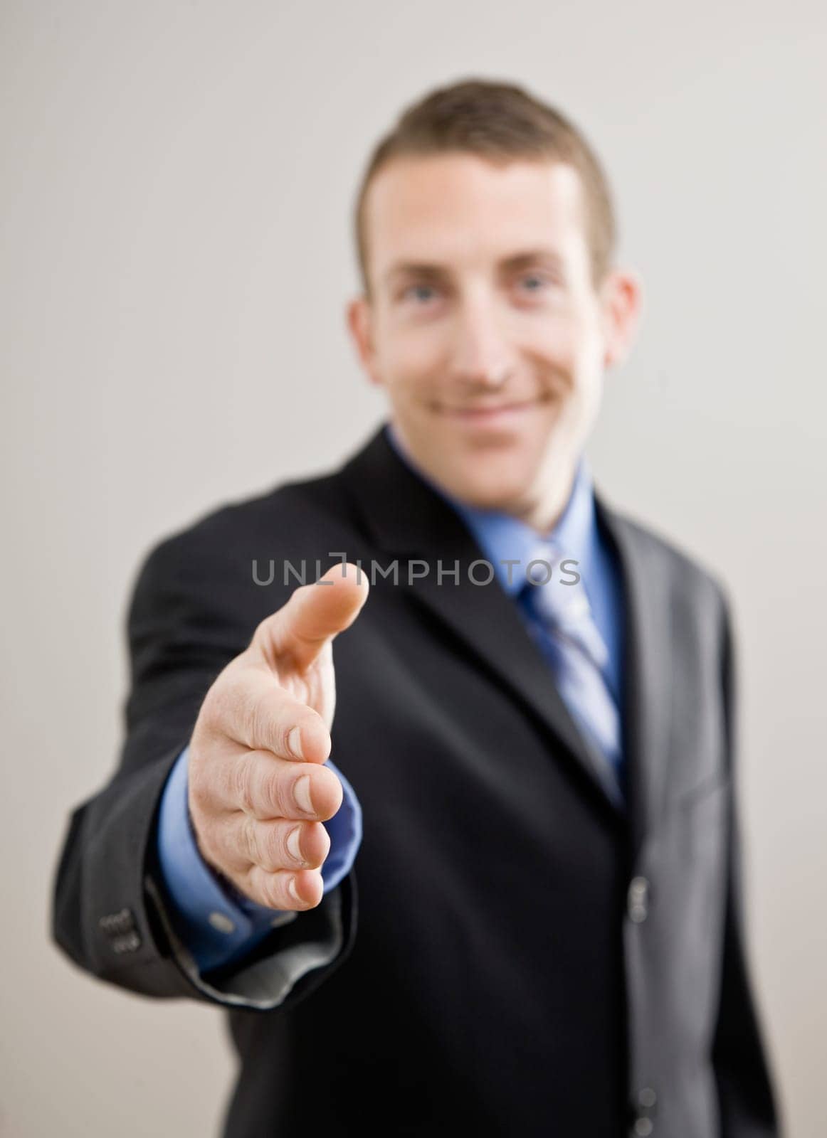 Business man offers hand to shake. Vertically framed shot.