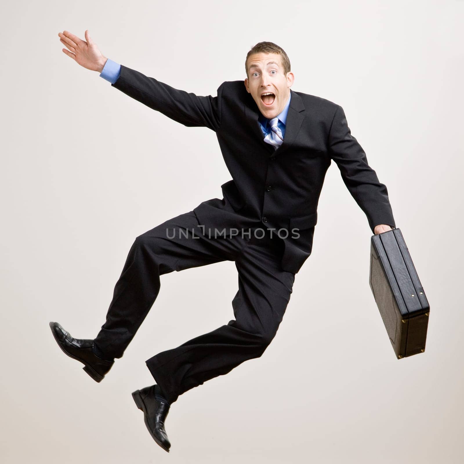 Business man jumping in the air and clicking heels. Square format.
