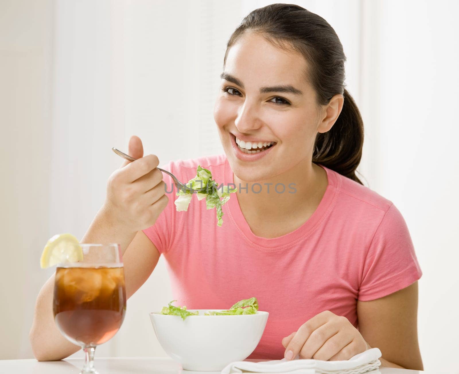 Young woman eating green salad. Horizontally framed shot.