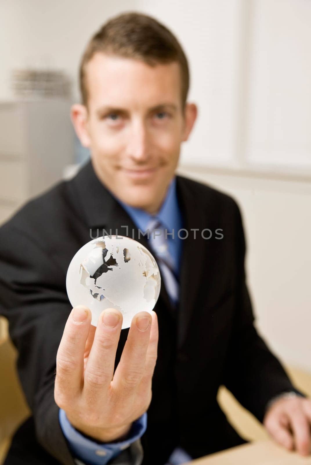 Young businessman holding globe. Vertically framed shot.