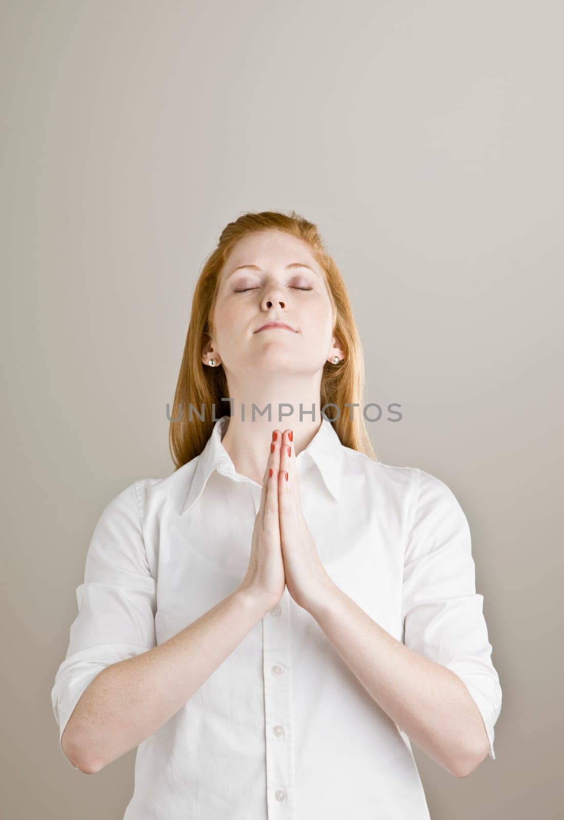 Young woman holding hands together while praying. Vertically framed shot.