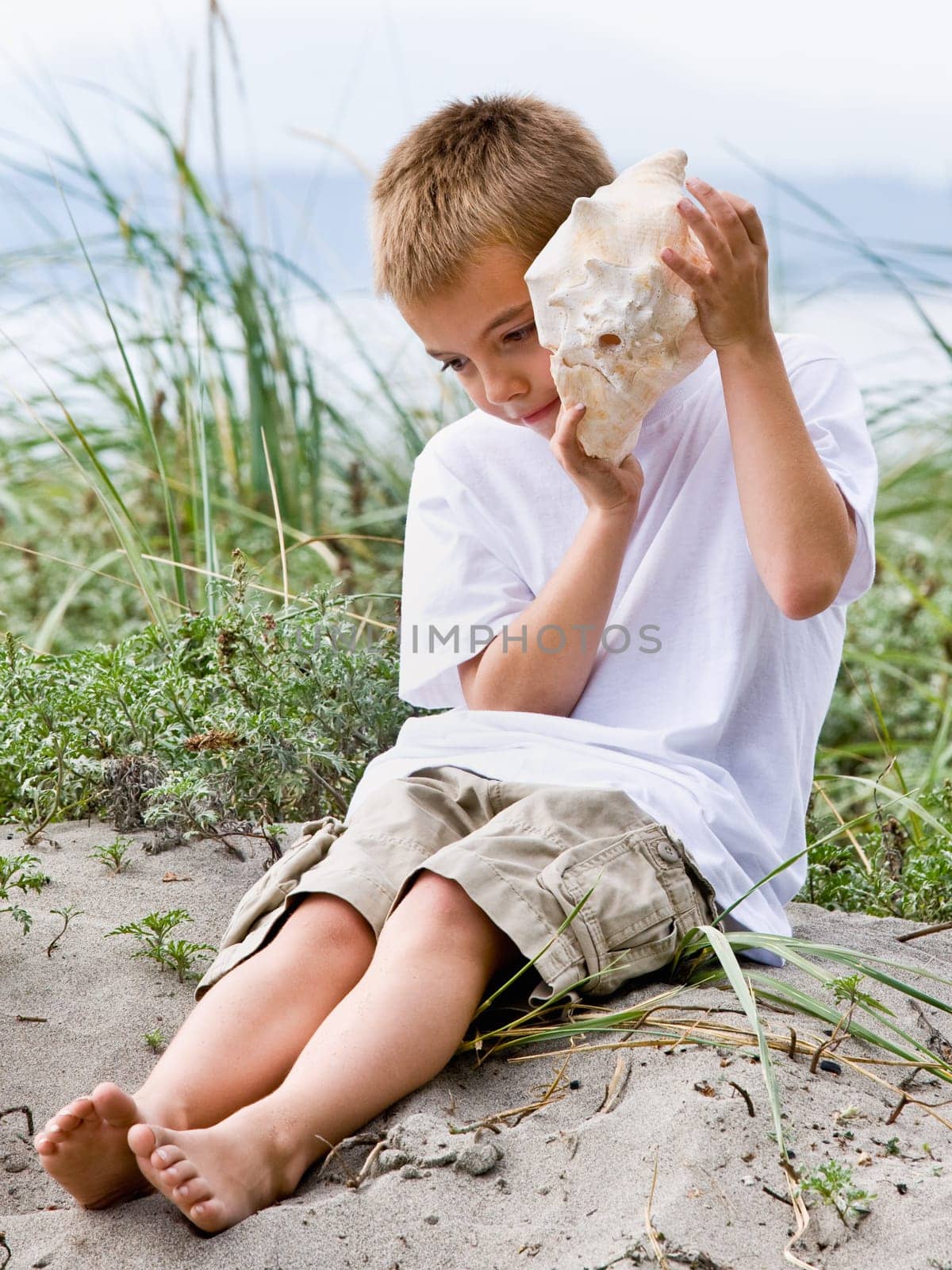 Boy listening to seashell at beach