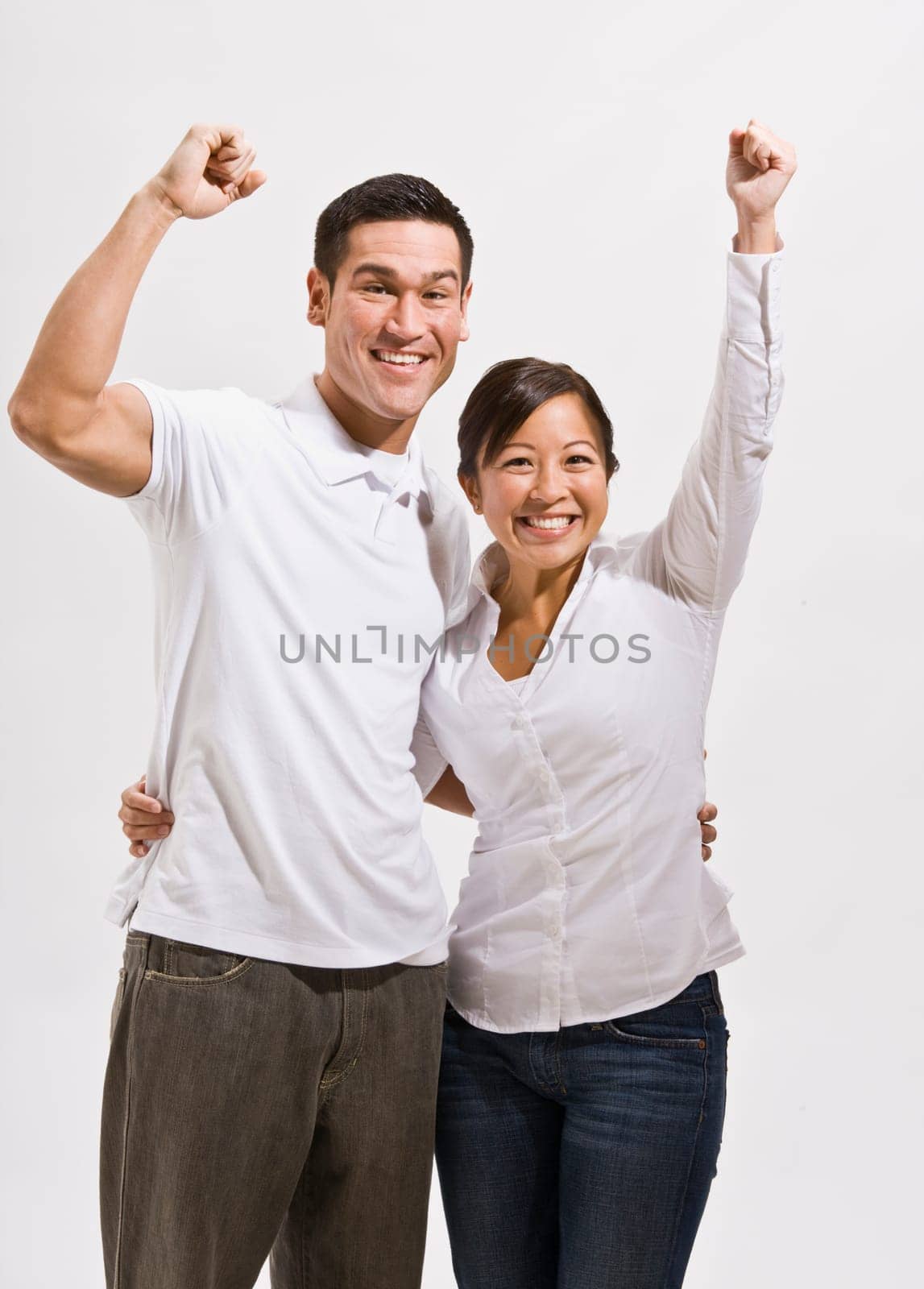 An attractive young asian couple cheering with their fists in the air. They are smiling at the camera. Vertically framed shot.