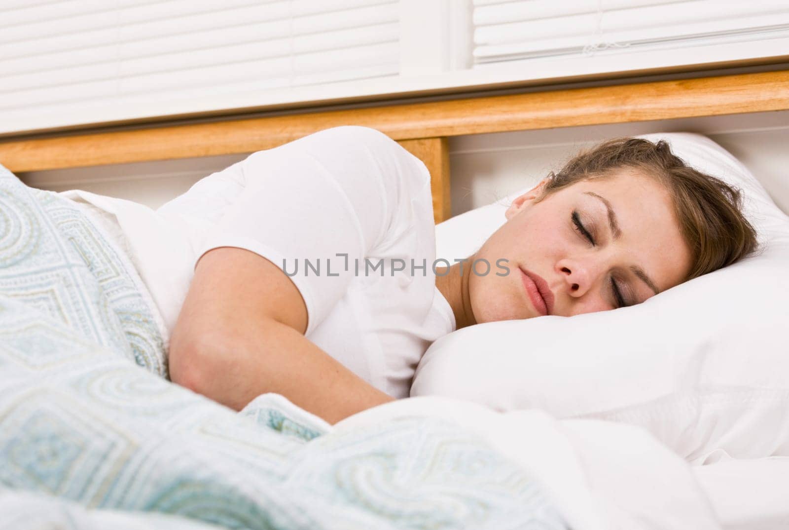 A beautiful young woman is sleeping in her bed. Horizontally framed shot.