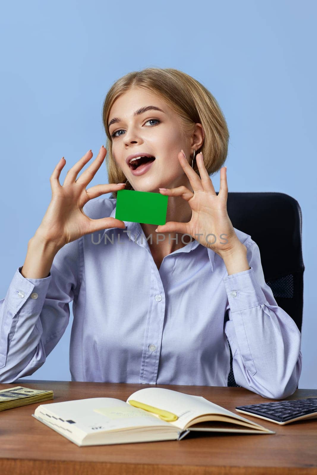 very excited business woman holding plastic credit card on blue background