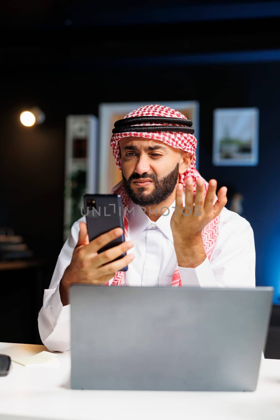 Arab man engrossed in a conference call by DCStudio