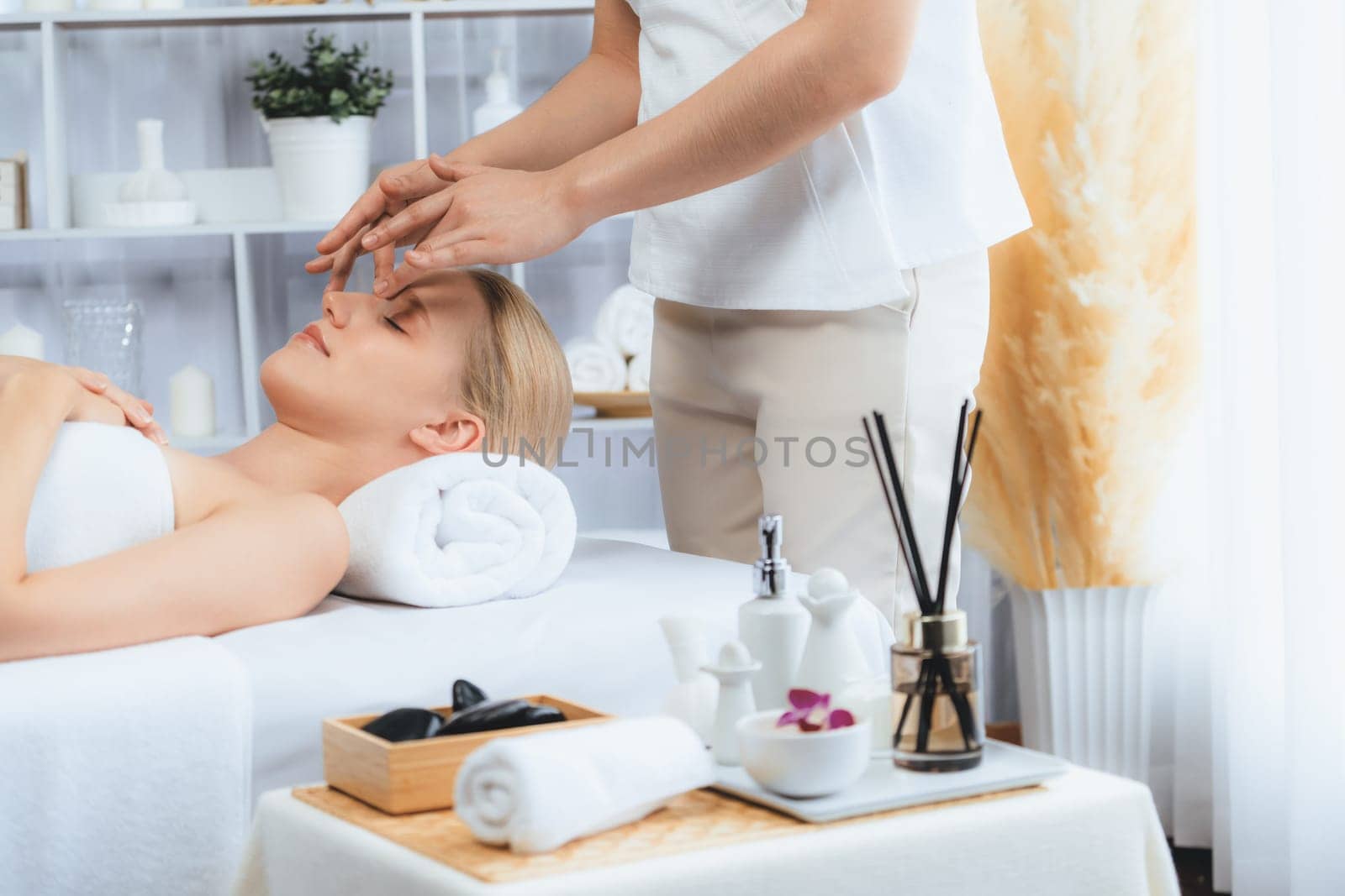 Caucasian woman enjoying relaxing anti-stress head massage and pampering facial beauty skin recreation leisure in dayspa modern light ambient at luxury resort or hotel spa salon. Quiescent