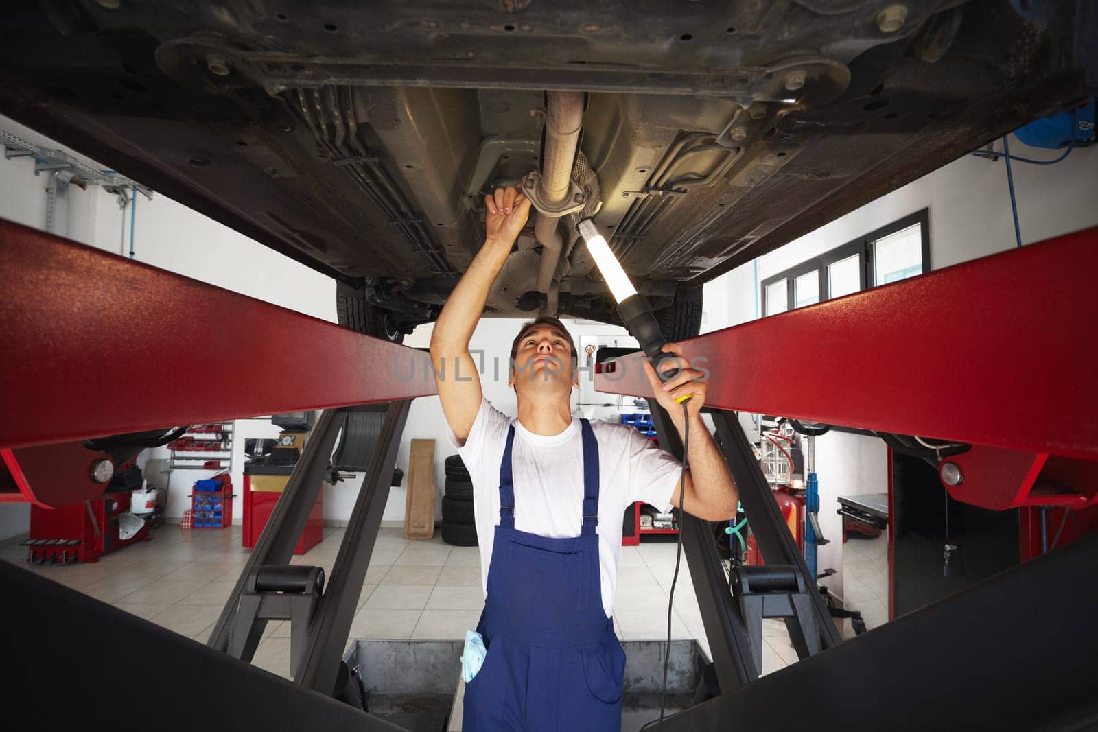mechanic standing under car engine and holding lamp. Copy space