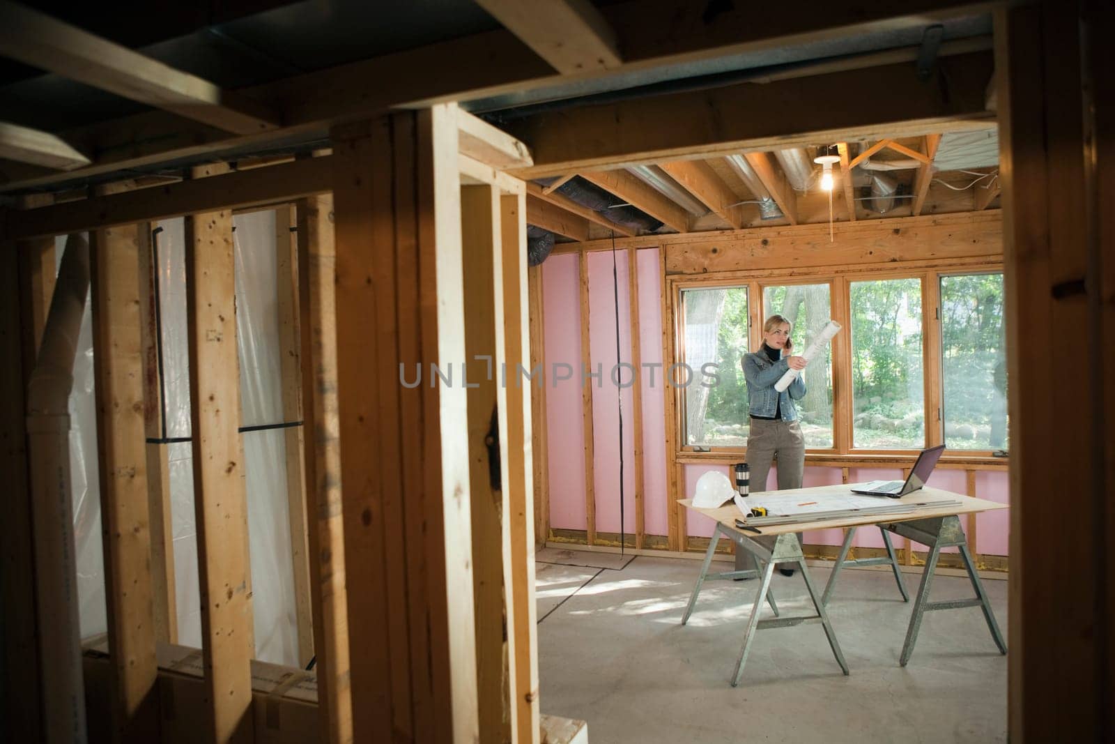 A young woman is talking on the phone at a construction site.  Horizontally framed shot.