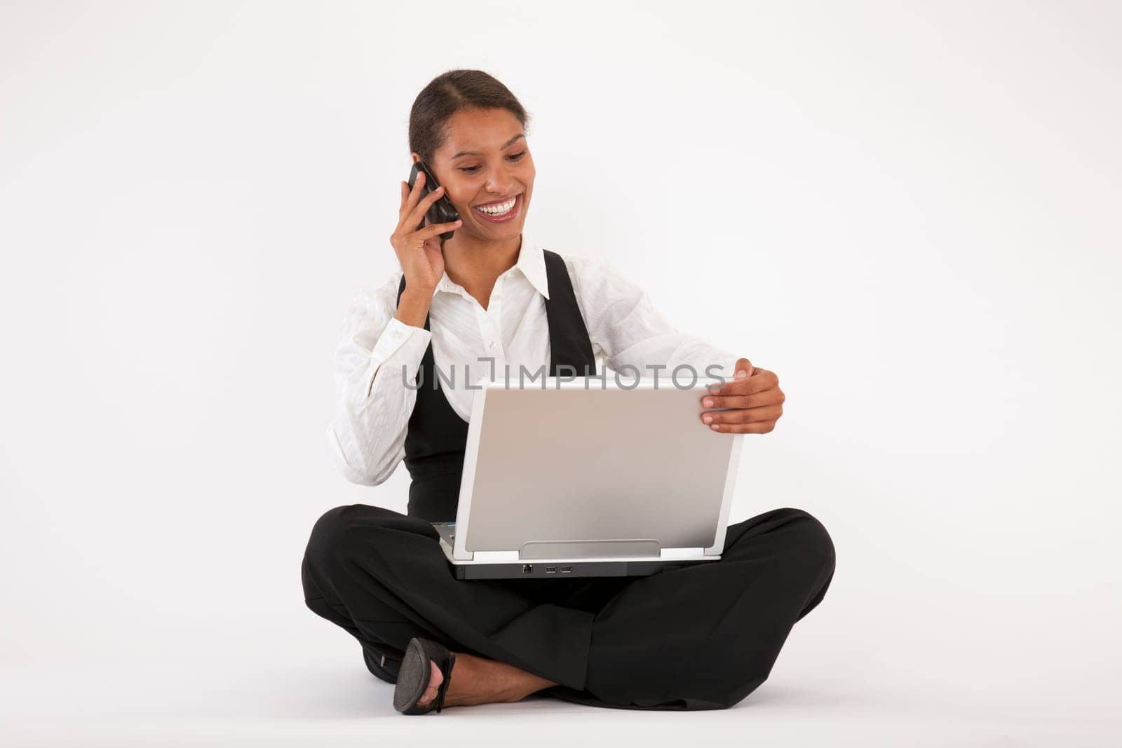Young woman sitting on floor using laptop and cell phone. Horizontally format.