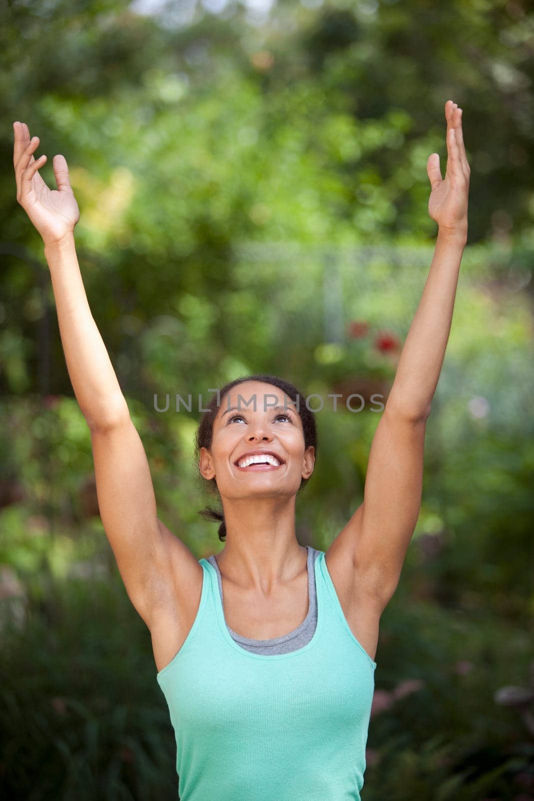 Young woman with arms raised in outdoor setting. Vertically framed shot.