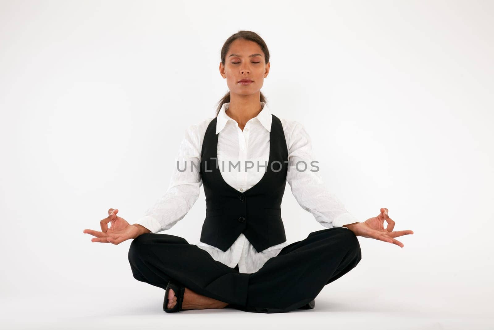 Young woman sitting cross legged and meditating. Horizontally framed shot.