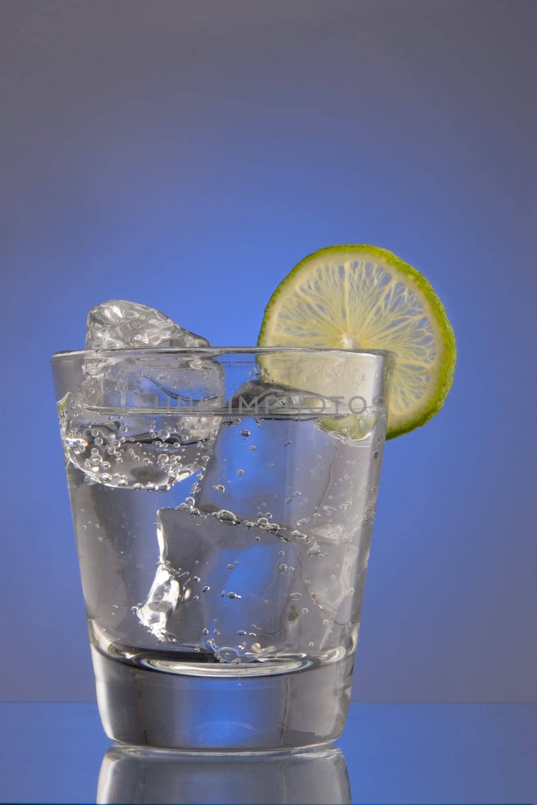 Club Soda on the rocks with lime slice garnish on plain background