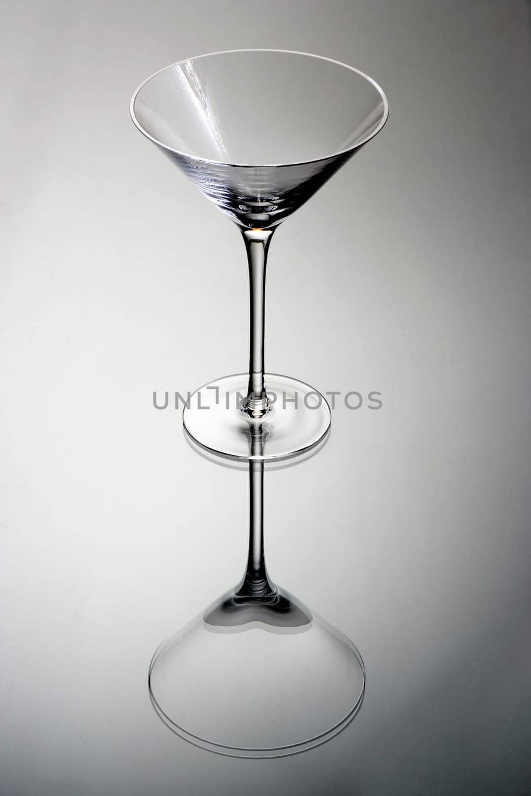 Empty martini glass on a grey background with reflection