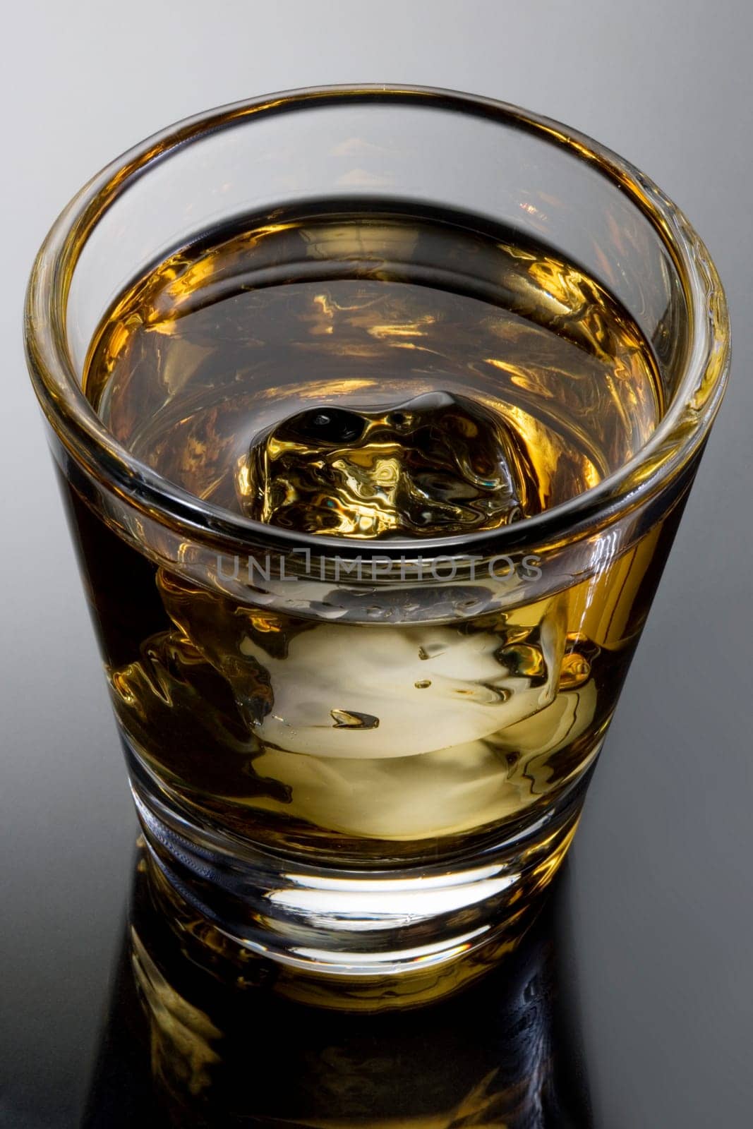 Scotch on the rocks on a grey background with reflection