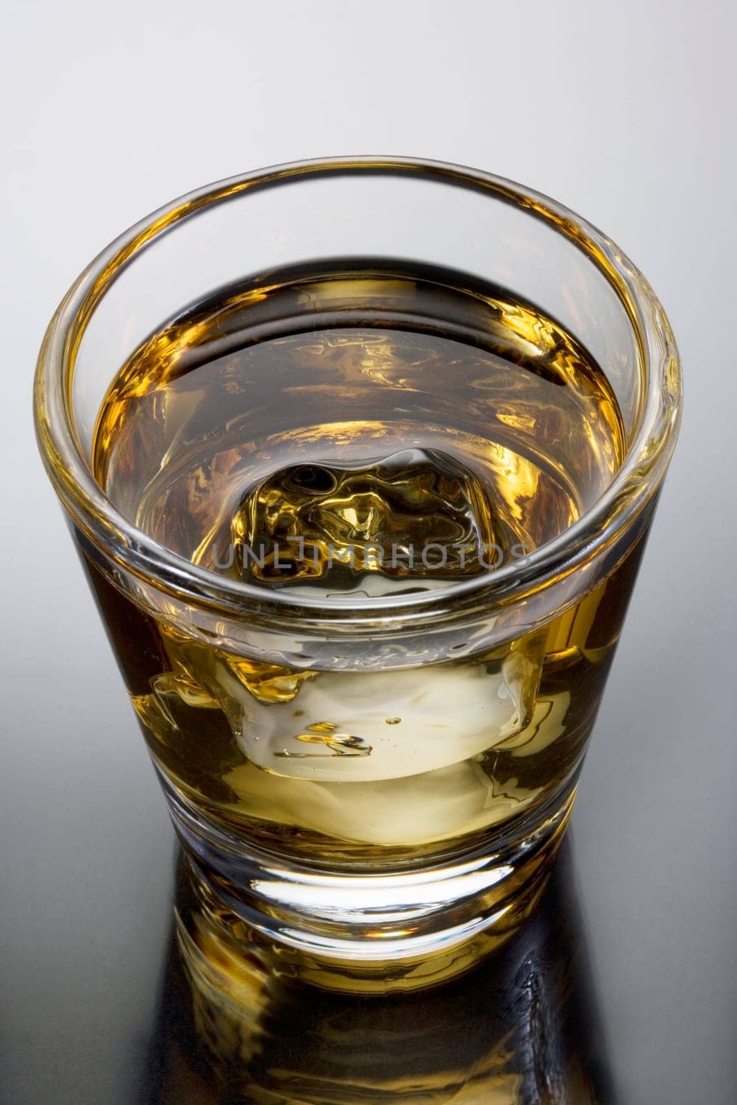 Scotch on the rocks on a grey background with reflection