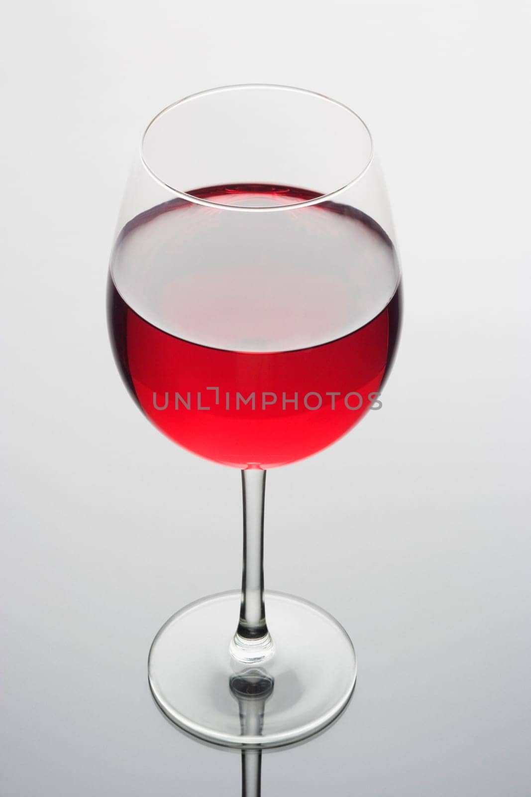 Red wine in a glass on a plain background with reflection