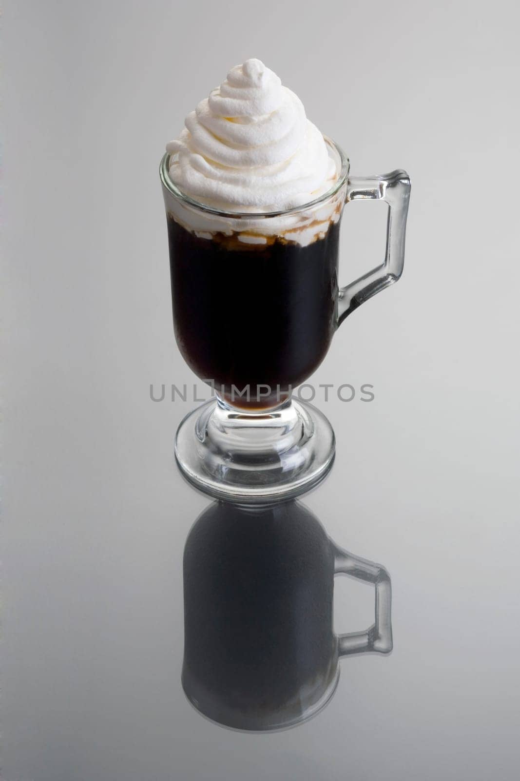 Irish Coffee mixed drink on grey background with reflection