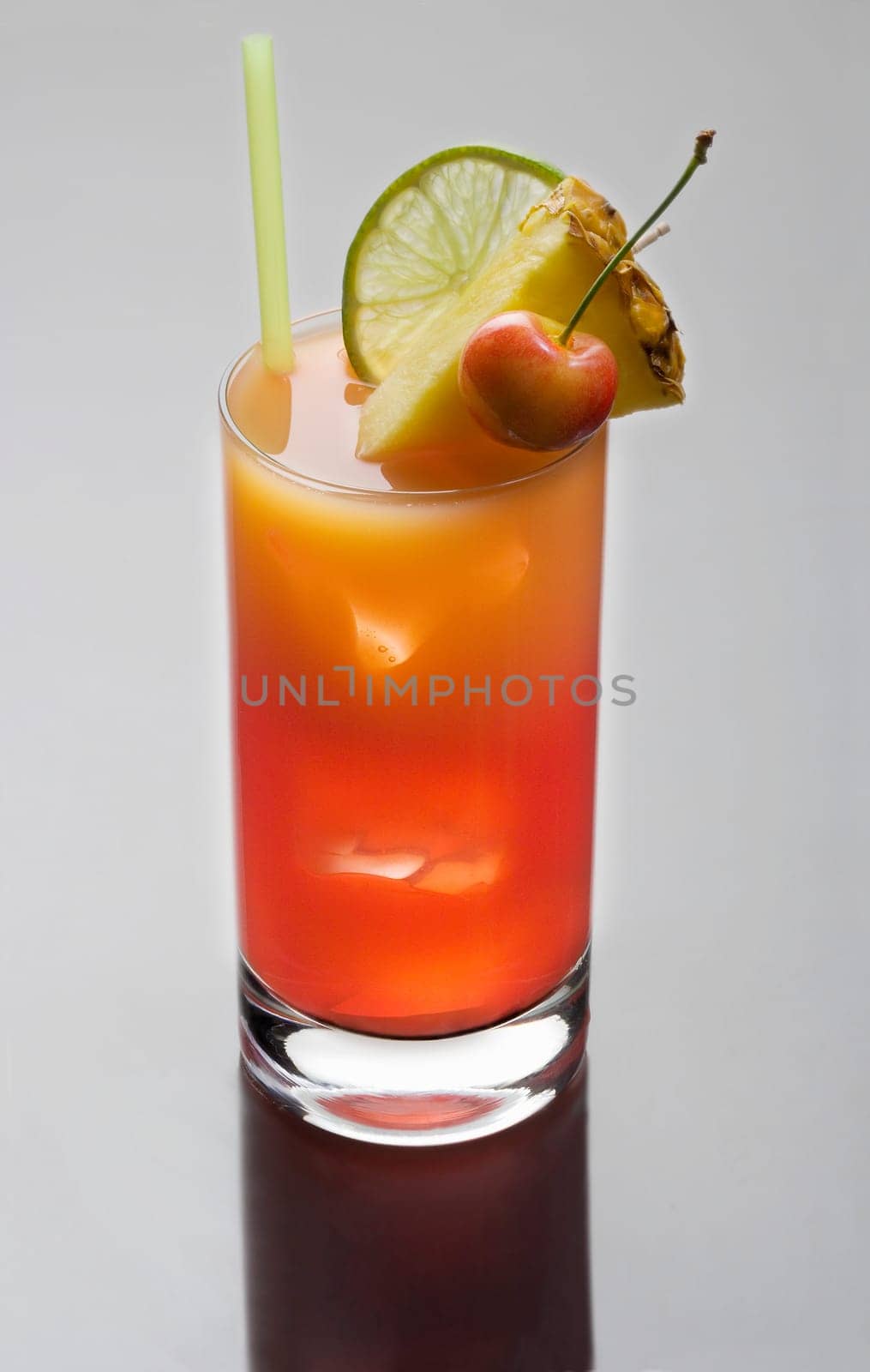 Mai Tai mixed drink with fruit garnish on a plain grey background with reflection