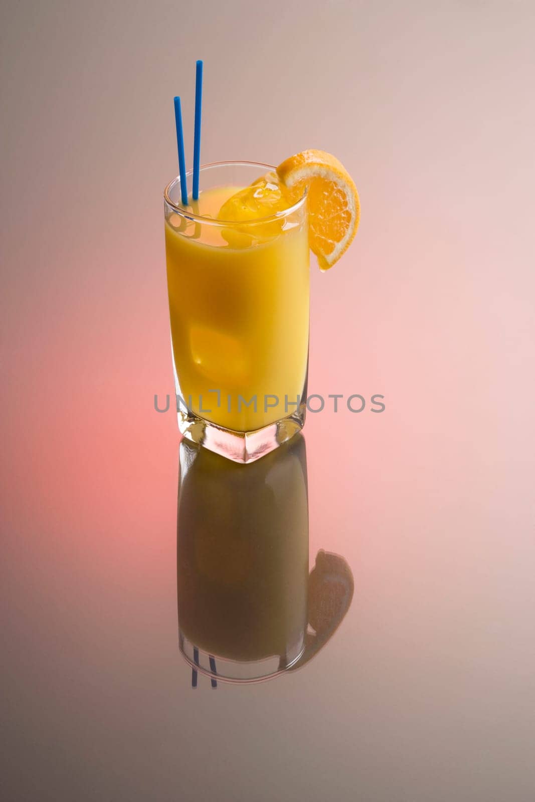 Screwdriver cocktail with orange garnish on plain background with reflection